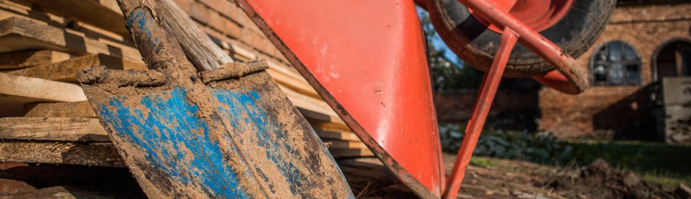 Photo of a red wheelbarrow and dirty shovel